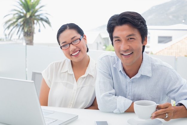 Sorridente casal com café da manhã juntos usando laptop