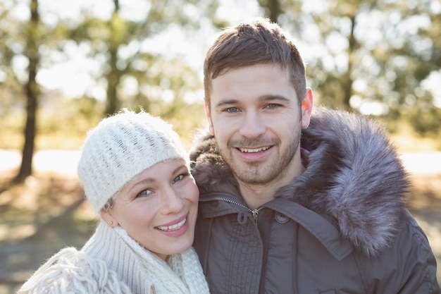 Sorridente casal em roupas de inverno na floresta