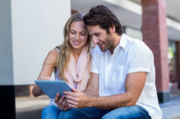 Sorridente casal sentado e usando a tablet computador em conjunto