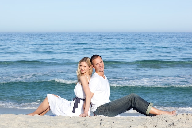 Sorridente casal sentado na areia