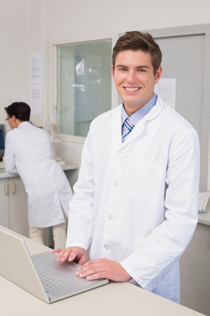 Sorridente cientista usando laptop