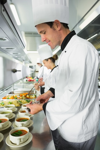 Sorridente cozinheiro chefe temperando sua sopa