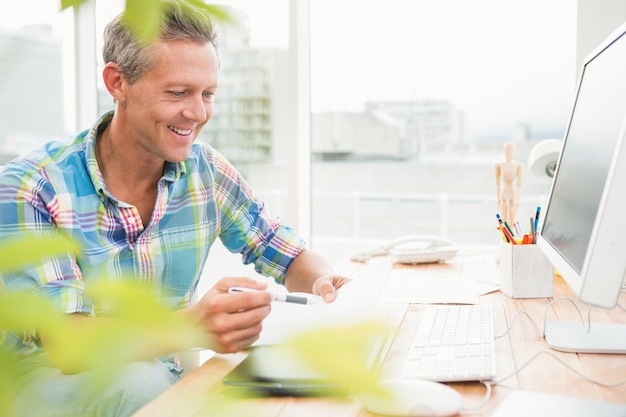 Sorridente designer casual trabalhando em sua mesa