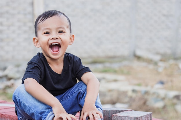 Sorridente e alegre garotinho asiático brincando ao ar livre