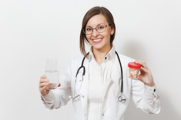 Sorridente e bela jovem médica com óculos de estetoscópio isolados no fundo branco. médica em vestido de médico segura o frasco com comprimidos de vidro de água. conceito de medicina de pessoal de saúde.