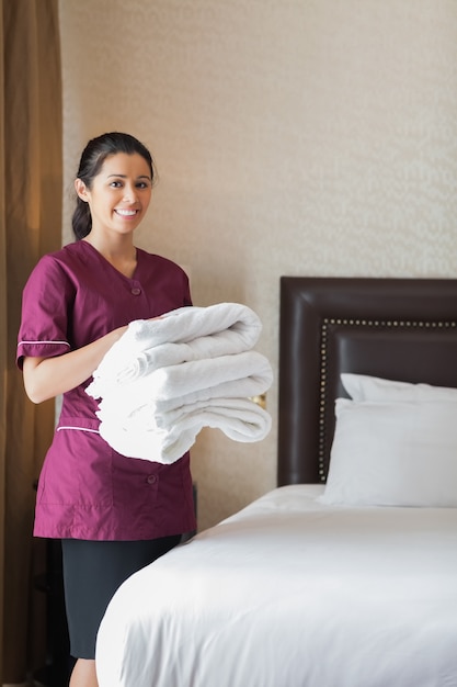 Sorridente empregada de hotel que segura toalhas