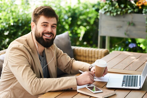 Sorridente empresário moderno trabalhando no café