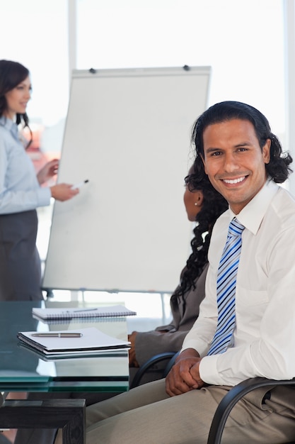 Sorridente empresário sentado em uma mesa ao ouvir uma apresentação