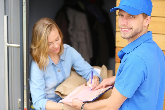 Sorridente entregador de uniforme azul entregando a caixa de encomendas para o conceito de serviço de correio destinatário Sorridente entregador de uniforme azul