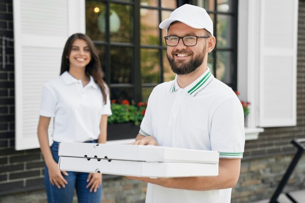 Sorridente entregador segurando caixas de pizza