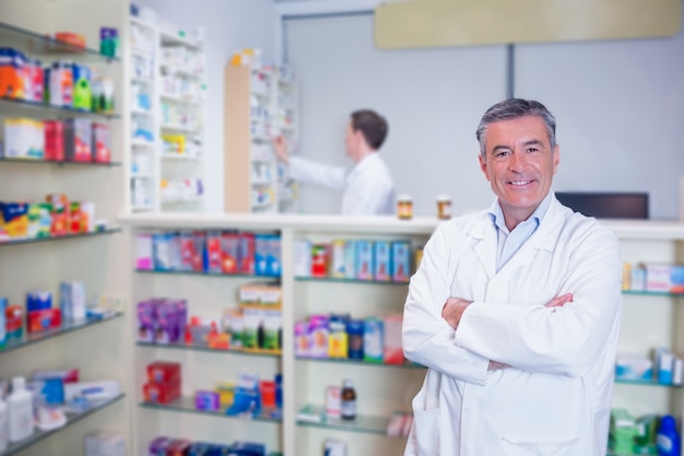 Sorridente farmacêutico de pé com os braços cruzados