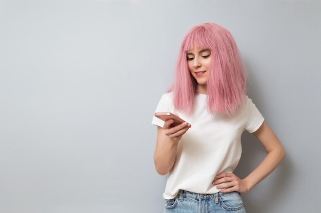 Sorridente garota de cabelo rosa escrevendo mensagem no smartphone. Aprendizagem online, navegação na internet, conceito de comunicação online