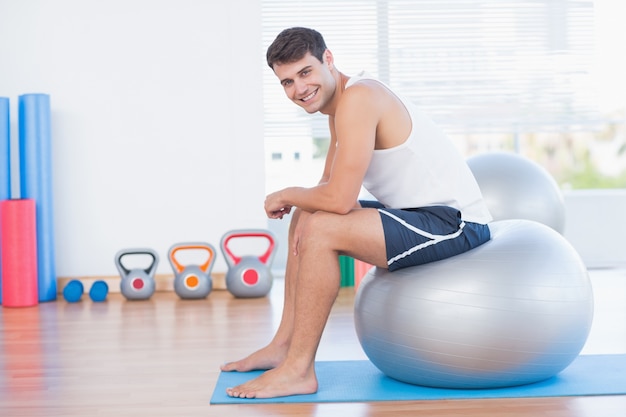 Sorridente, homem, sentando, exercício, bola, olhar, câmera