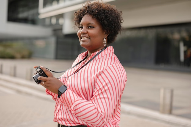 Sorridente jovem afro com câmera fotográfica retrô