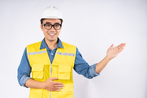 Sorridente jovem engenheiro civil asiático usando capacete de capacete em pé sobre fundo branco isolado. Conceito de serviço mecânico.