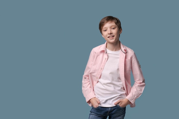 Sorridente jovem engraçado em camiseta branca casual e camisa rosa posando na luz
