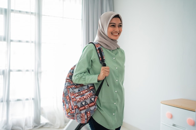 Sorridente jovem hijab viajante carregando sua bolsa e segurando a mala