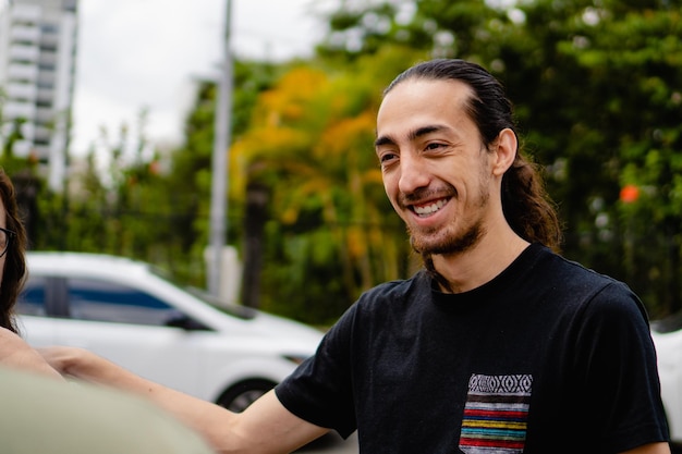 Sorridente jovem latino com cabelo comprido conversando com seus amigos