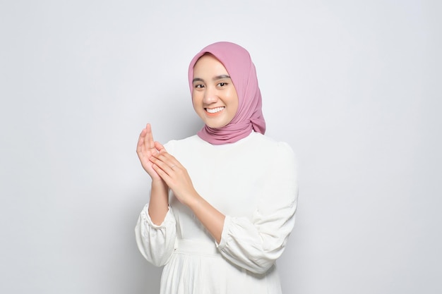Sorridente jovem muçulmana asiática batendo palmas celebrando o sucesso com expressões faciais felizes isoladas sobre fundo branco
