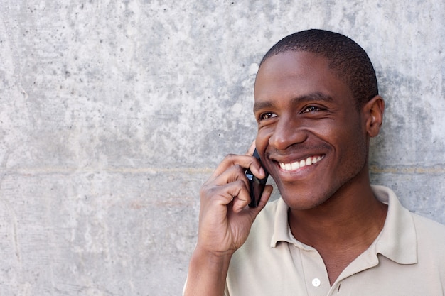 sorridente jovem rapaz africano ouvindo o celular