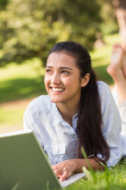 Sorridente jovem usando laptop no parque