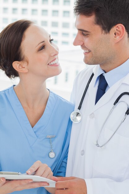 Sorridente médico e cirurgião atraente olhando uns para os outros