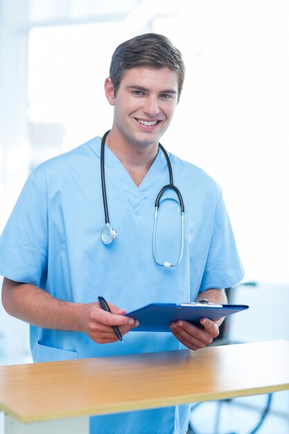 Sorridente médico olhando câmera e segurando prancheta