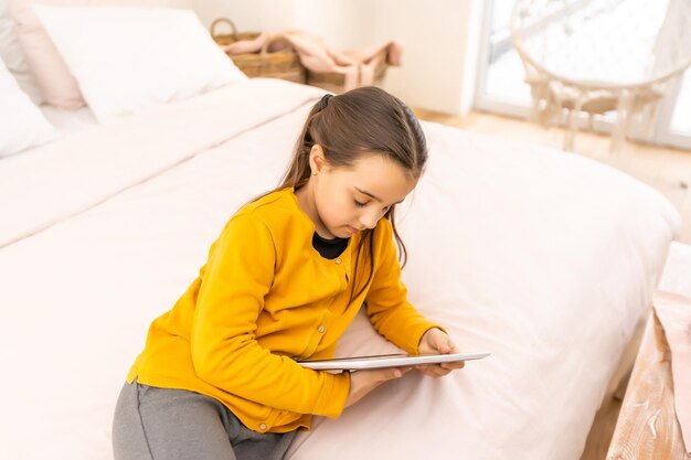 Sorridente menina deitada no sofá confortável, gostando de jogar