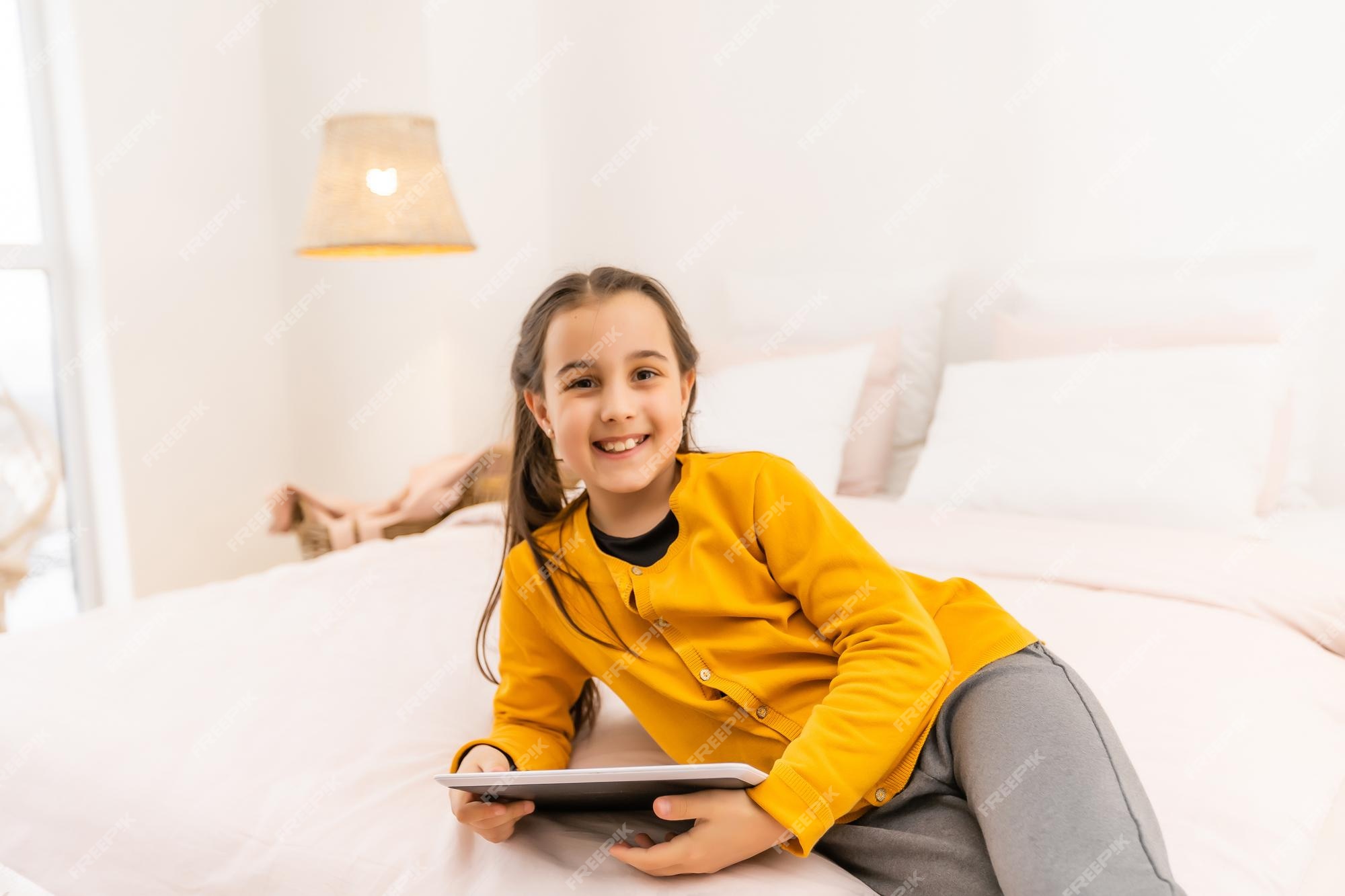 Sorridente menina deitada no sofá confortável, gostando de jogar jogo  online no computador tablet digital. viciado em tecnologia, criança feliz  usando aplicativos engraçados, informações de navegação na web.