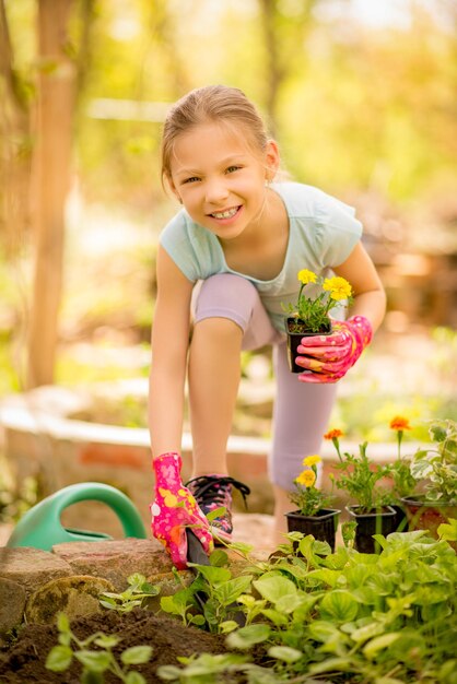 Sorridente menina plantando flores no jardim.