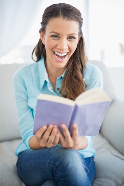 Foto sorridente, mulher, sentando, sofá, segurando, livro