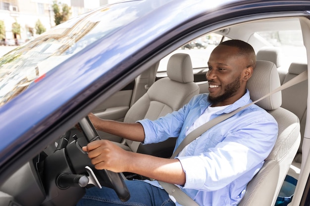 Sorridente negro dirigindo carro novo na cidade