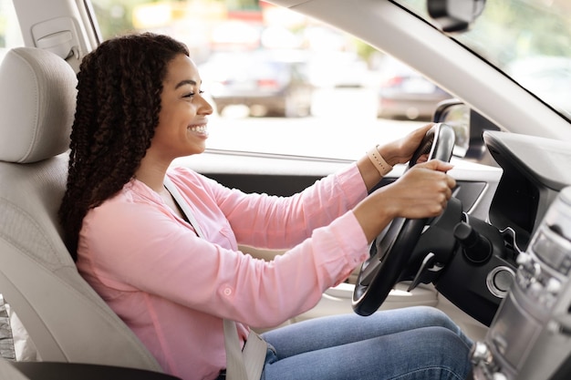 Foto sorridente senhora negra testando seu carro novo