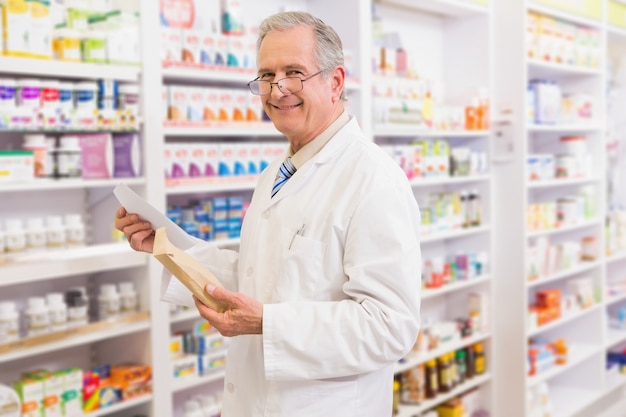 Sorridente sênior farmacêutico segurando envelope e prescrição