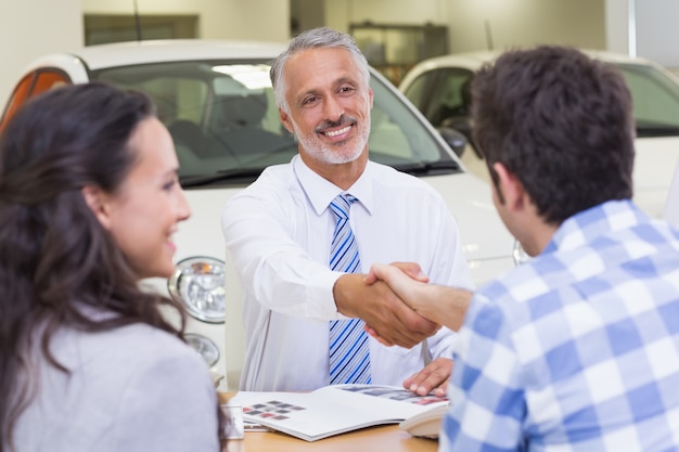 Sorridente vendedor agitando a mão de um cliente