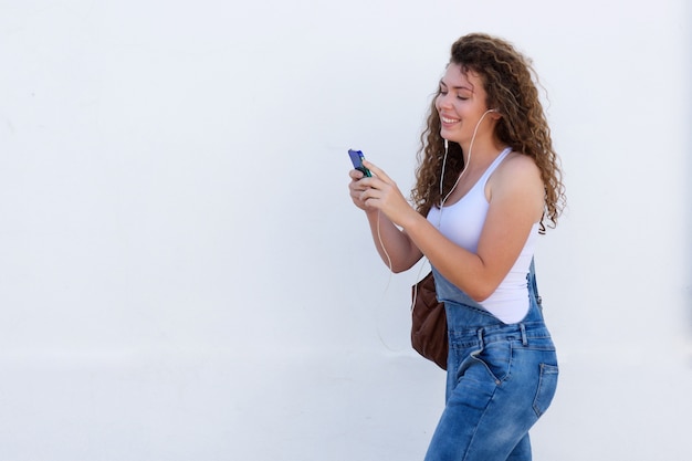 Sorrindo adolescente com celular e fones de ouvido andando