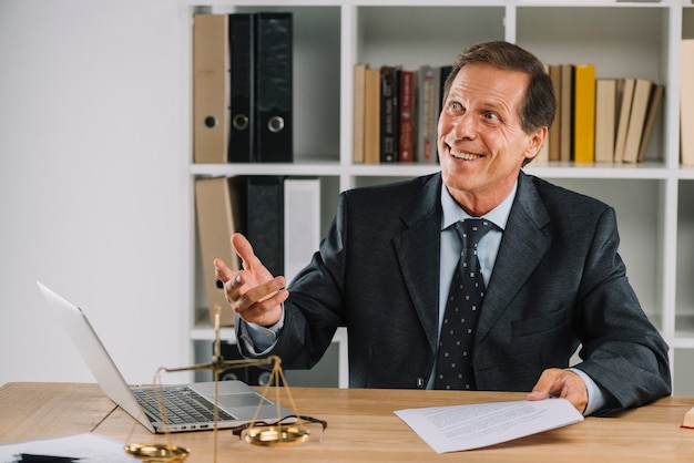 Foto sorrindo advogado maduro segurando o documento na mão no local de trabalho