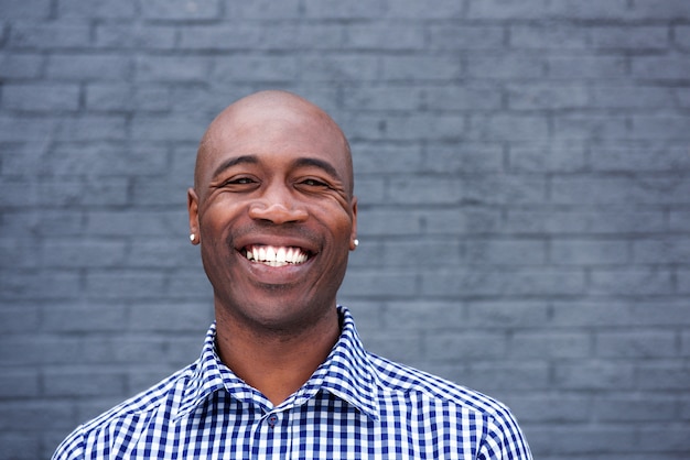 Sorrindo africano cara contra a parede cinza