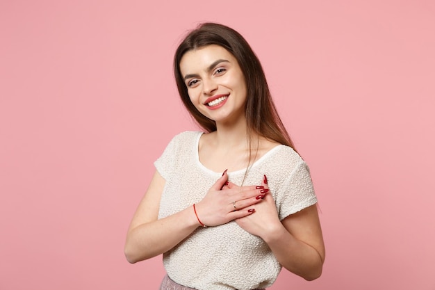 Sorrindo agradável jovem em roupas leves casuais posando isolado no fundo rosa, retrato de estúdio. Conceito de estilo de vida de emoções sinceras de pessoas. Mock up espaço de cópia. De mãos dadas no coração.