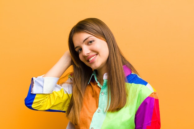 sorrindo alegre e casualmente, levando a mão à cabeça com um olhar positivo, feliz e confiante