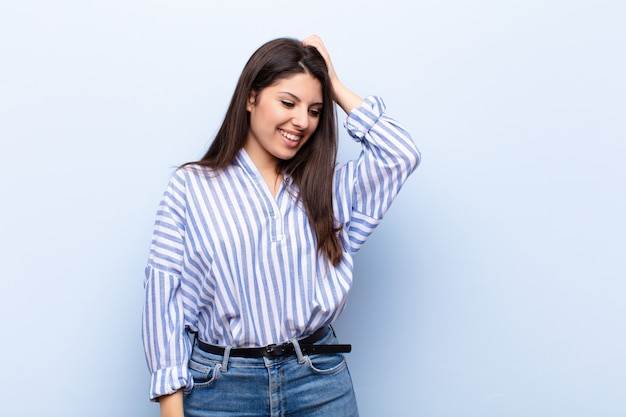 Sorrindo alegre e casualmente, levando a mão à cabeça com um olhar positivo, feliz e confiante