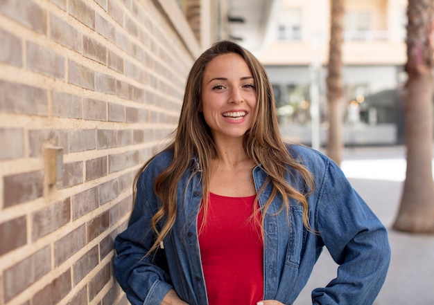 Sorrindo alegremente com as mãos no quadril e atitude confiante, orgulhosa e amigável