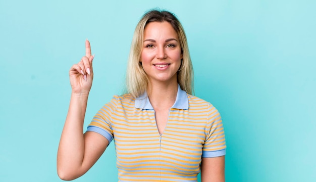 Sorrindo alegremente e alegremente apontando para cima com uma mão para copiar o espaço