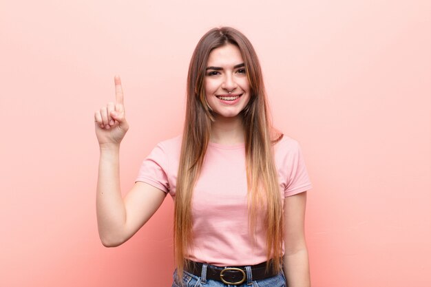 Sorrindo alegremente e alegremente, apontando para cima com uma mão para copiar o espaço