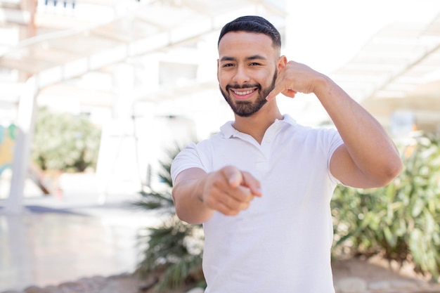 Sorrindo alegremente e apontando para a câmera enquanto faz uma ligação, você gesticula mais tarde falando no telefone