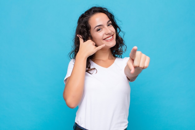 sorrindo alegremente e apontando para a câmera enquanto faz uma ligação, você gesticula mais tarde, falando no telefone