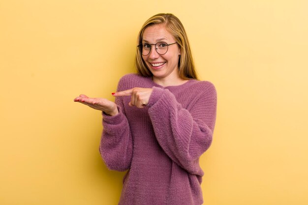 Sorrindo alegremente e apontando para copiar o espaço na palma da mão mostrando ou anunciando um objeto