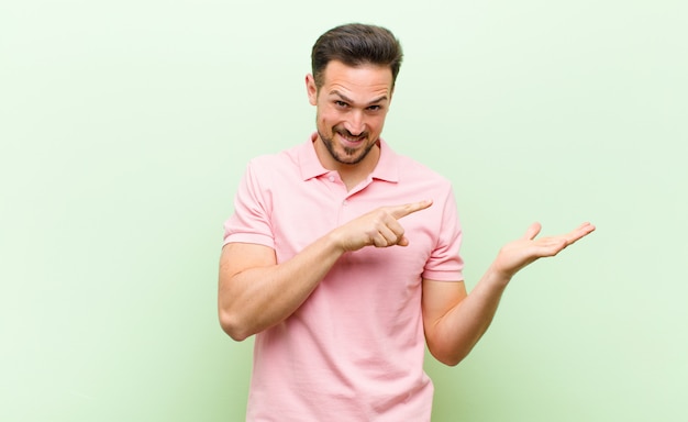 sorrindo alegremente e apontando para copiar o espaço na palma da mão, mostrando ou anunciando um objeto