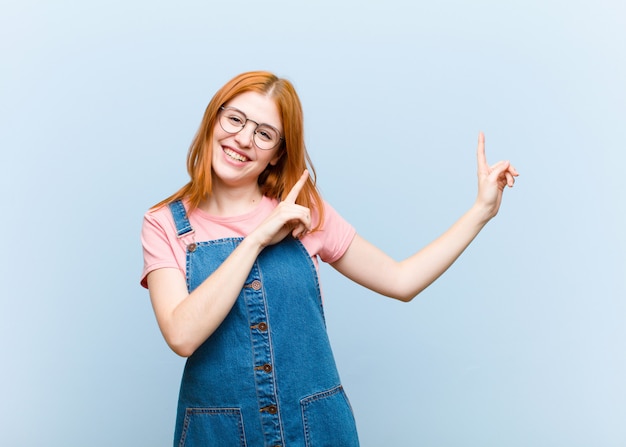 sorrindo alegremente e apontando para o lado e para cima com as duas mãos, mostrando o objeto no espaço da cópia