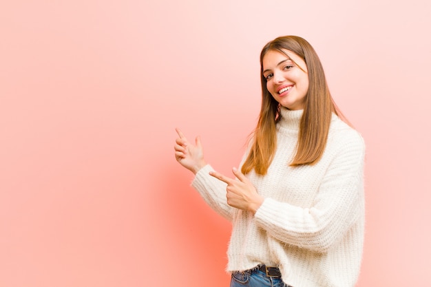 sorrindo alegremente e apontando para o lado e para cima com as duas mãos, mostrando o objeto no espaço da cópia